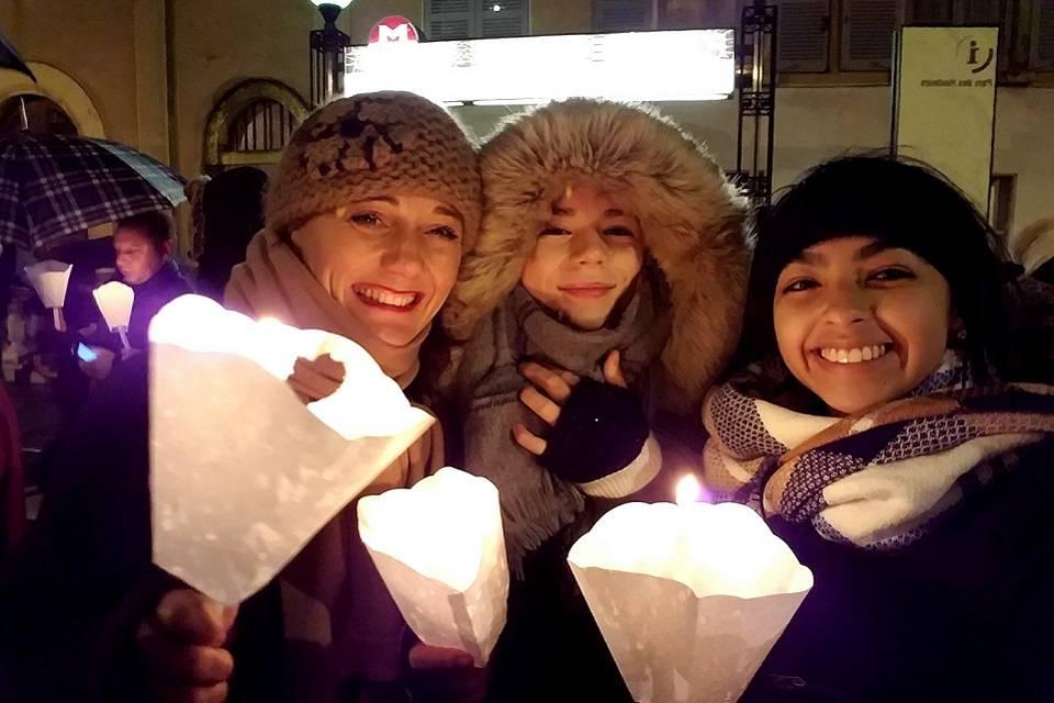 有寄宿家庭成员的学生, 穿冬装, 在户外节日上, 拿着纸烛台的蜡烛.
