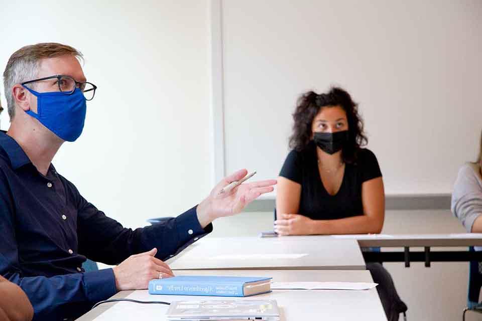 两个戴口罩的学生坐在教室的桌子旁