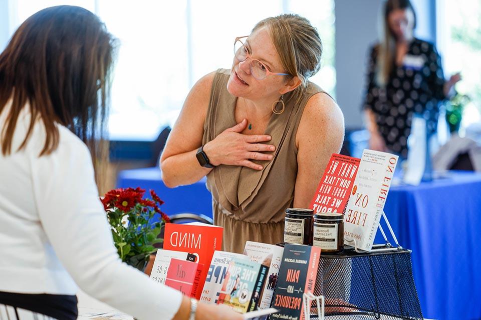 Employee at a book fair in front of a table of books