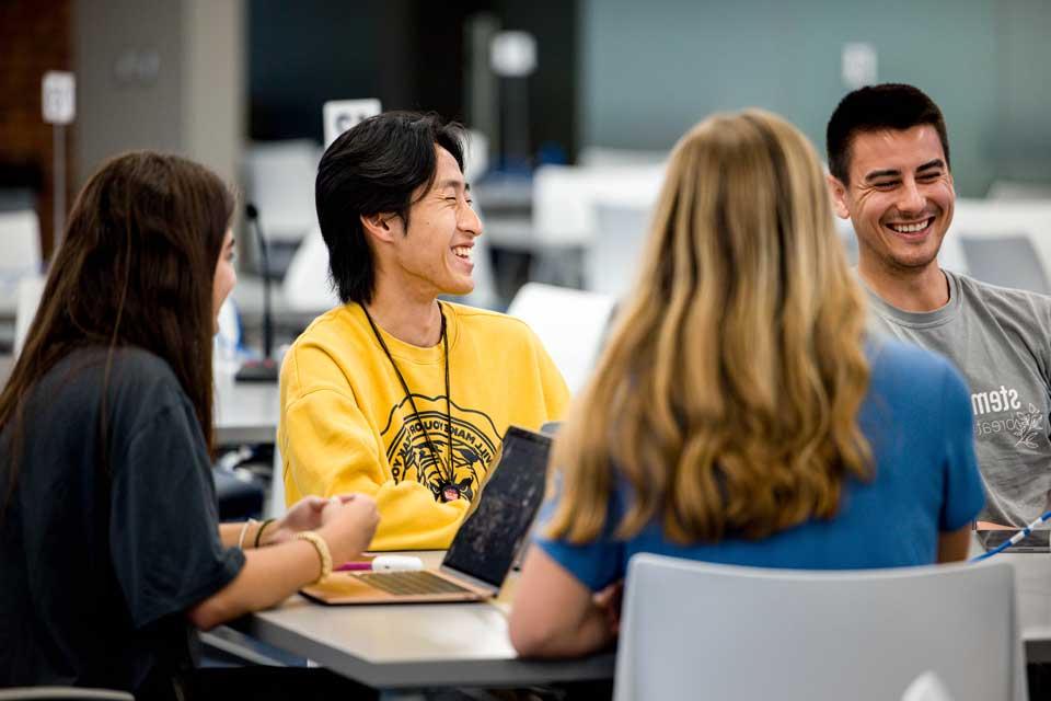 在大学教室里，学生们围坐在桌子旁互动