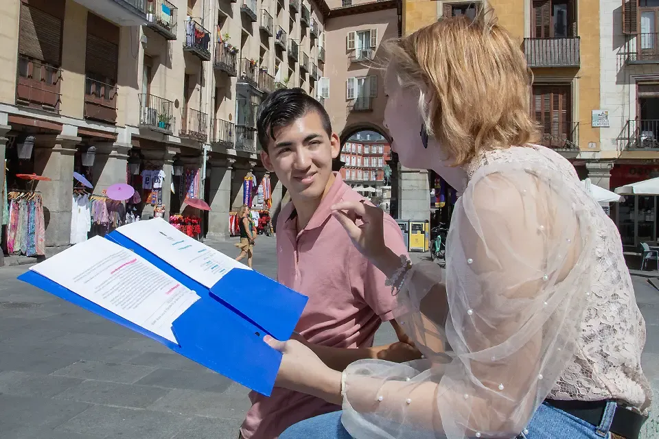 Two students with a notebook talking in the center of Madrid.