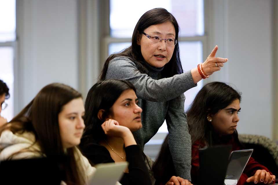 A female professor instructs a row of students