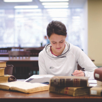 A student studies a manuscript in Pius Library
