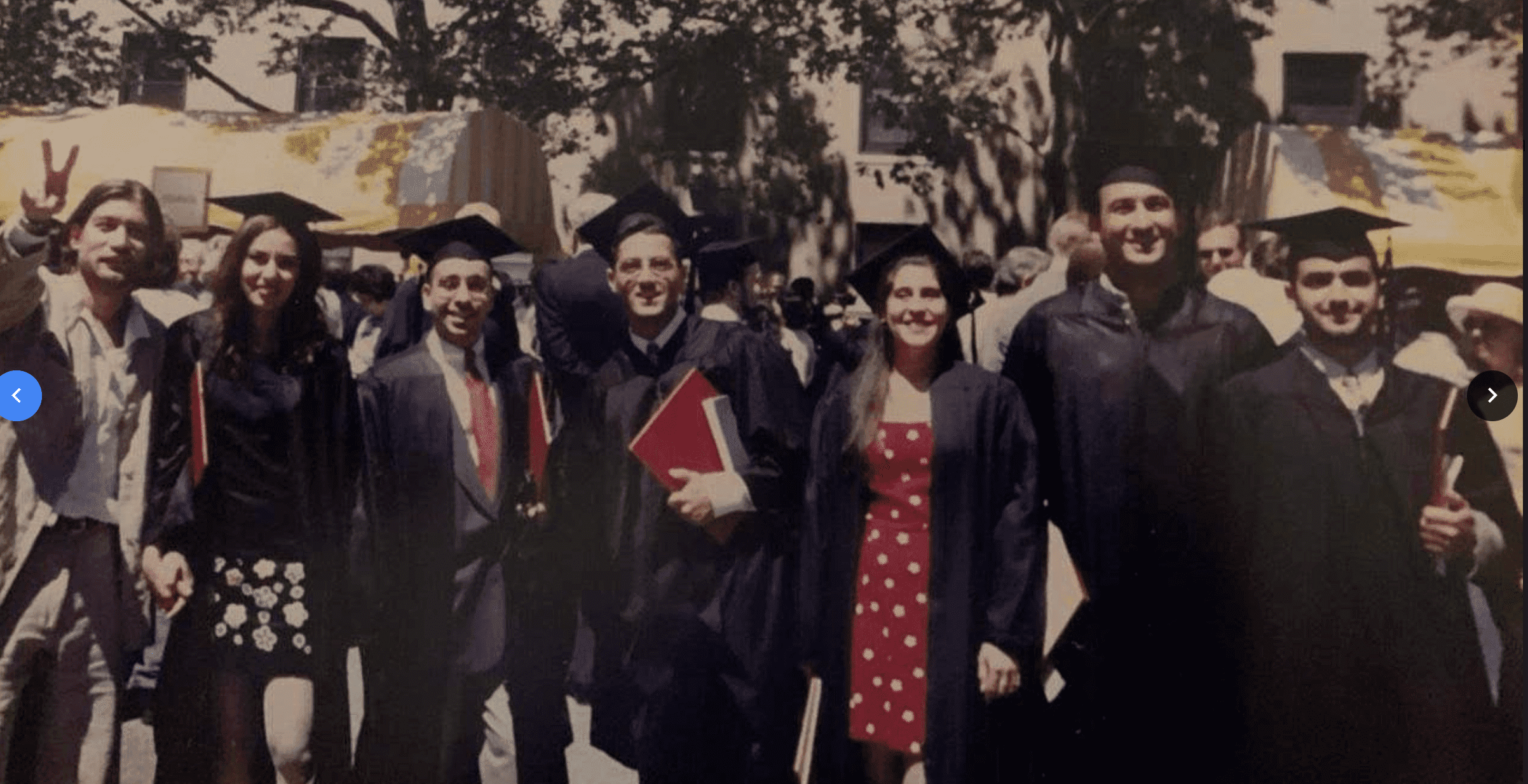 一群头戴帽子、身穿长袍的毕业生对着镜头微笑.
