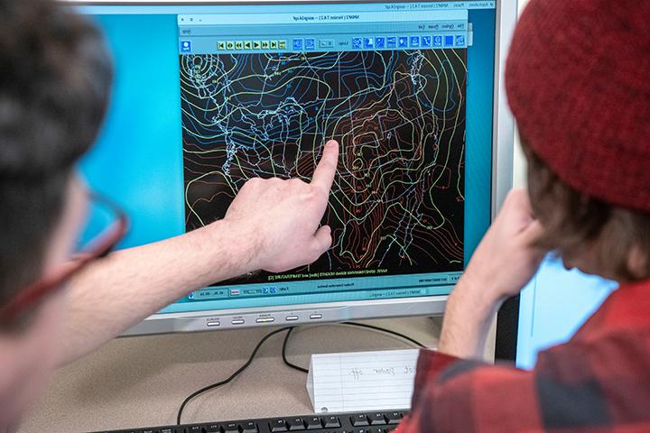 Meterology students looking at a computer screen with weather information
